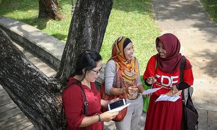 Domestic worker Endang Wiyanti (at right), who is volunteering with the Centre for Domestic Employees, giving out brochures yesterday to fellow domestic workers Sofiah Supridi (centre) and Sumiri.