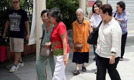 Madam Chung Khin Chun (in orange top) leaving the State Courts with her relative and friends after a hearing earlier this month.