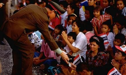 King Bhumibol greeting his people and giving out cash, in this photo taken in 1990. He and Queen Sirikit gave out tens of thousands of blankets, towels, clothes and school uniforms to Thais every year on their tours, during which he actively engaged 