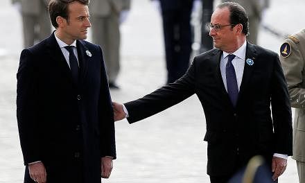Outgoing French President Francois Hollande (right) reaching out to President-elect Emmanuel Macron as they attended a ceremony to mark the end of World War II at the Tomb of the Unknown Soldier at the Arc de Triomphe in Paris yesterday. Above: Frenc