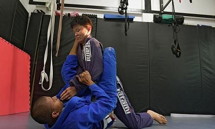 Ms Marilyn Cheng learning to pin down an opponent during her Brazilian jiu-jitsu class.