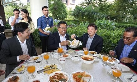 Malaysia's Minister in the Prime Minister's Department Abdul Rahman Dahlan with Coordinating Minister for Infrastructure Khaw Boon Wan, who is also Transport Minister, enjoying durian during a tea break at Afiniti Medini, after a site visit to the mi