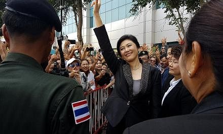 Ousted Thai prime minister Yingluck Shinawatra greeting supporters on leaving the Supreme Court in Bangkok yesterday.