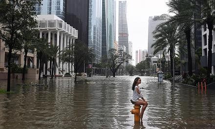 A Miami resident keeping her cool as the street turns into a river around her on Sunday. Irma's force might be diminished, but its potential for flash floods and staggering rainfall was not. Government forecasters said up to 38cm of rain was possible