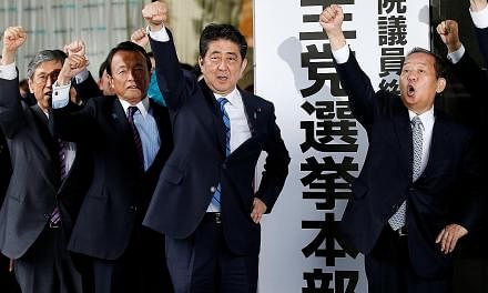 Above: Japanese Prime Minister Shinzo Abe and his party's lawmakers, including Mr Taro Aso (left) and Mr Toshihiro Nikai (right), pledging to emerge victorious in the upcoming Lower House elections at the LDP's headquarters in Tokyo yesterday.