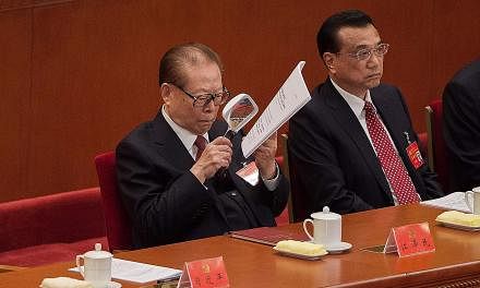 Former Chinese president Jiang Zemin reading the text of President Xi Jinping's speech as he listened to the address beside Premier Li Keqiang during the opening of the 19th Communist Party Congress in Beijing yesterday. The 91-year-old former party 