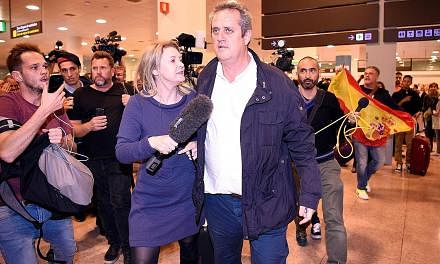 Catalonia's former interior chief, Mr Joaquim Forn, being followed by journalists as a man with a Spanish flag shouts at him upon his arrival at El Prat airport in Barcelona after flying from Brussels on Tuesday.