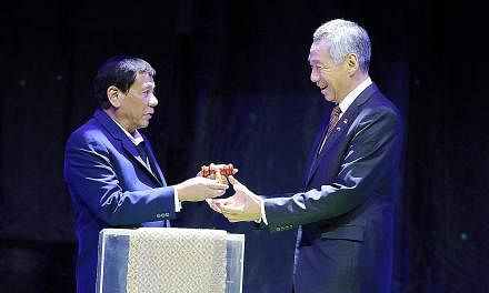Philippine President Rodrigo Duterte giving Prime Minister Lee Hsien Loong a symbolic gavel to mark the handover of the rotating Asean chairmanship to Singapore at last night's closing ceremony for the 31st Asean Summit.