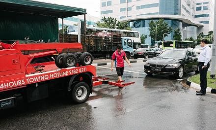 Mr Ricky Ng (right) waiting for his BMW car to be towed after he was caught in Monday's flood near the junction of Upper Changi Road and Bedok North Avenue 4. "The damage is quite bad as water got into the engine, exhaust and air intake system," he s