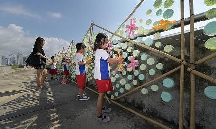 Pupils from PCF Sparkletots @ Zhenghua putting the finishing touches to a 120m caterpillar made of discarded plastic bottles at Marina Barrage. The art installation, which aims to raise awareness about plastic pollution, will be on display for a mont
