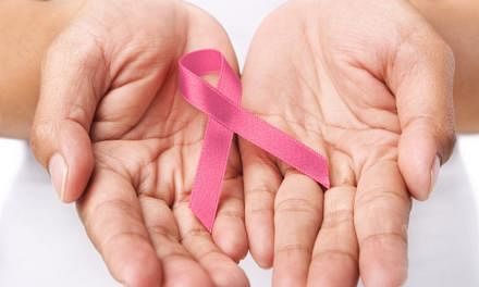 A woman holds up a pink ribbon in support of breast cancer awareness. 