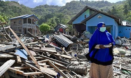 Ms Ipa Thamrin scavenging for scrap metal in front of her house which was destroyed by the 7.4 magnitude earthquake and tsunami. Children hit by the catastrophe begging for help or donations (above) from passing motorists along the road leading to Pa