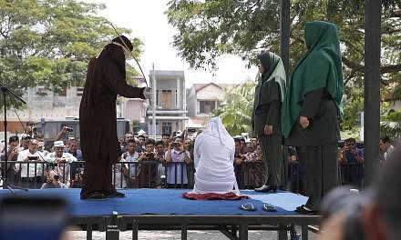 A woman being caned in public at the Lam Gugom Mosque in Banda Aceh in Indonesia's Aceh province earlier this month. Public floggings are well attended, with covered tents for dignitaries. Syariah enjoys popular support as it underscores the province