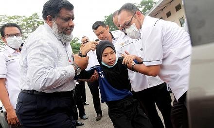 Johor Health Director Dr Selahuddeen Abd Aziz (far left) helping a student of Sekolah Kebangsaan Kopok, Pasir Gudang, who was suffering from breathing difficulties and nausea yesterday.