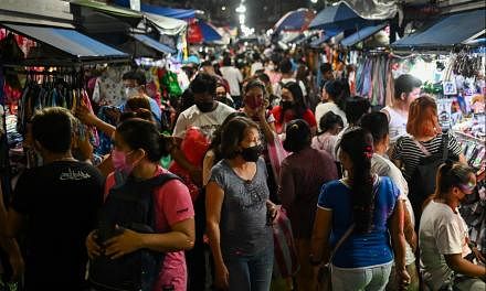 <p>People wearing face masks as protection against the coronavirus disease (COVID-19) walk past stores at a market in Manila, Philippines, December 18, 2021. REUTERS/Lisa Marie David</p>