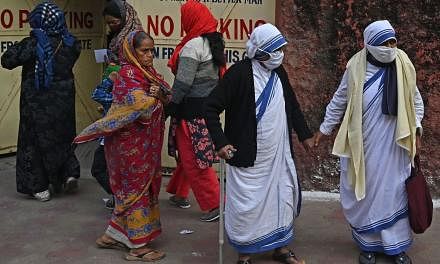 <p>Nuns from the Catholic Order of the Missionaries of Charity along with others walk after casting their vote at a polling station during the municipal corporation election in Kolkata on December 19, 2021. (Photo by Dibyangshu SARKAR / AFP)</p>