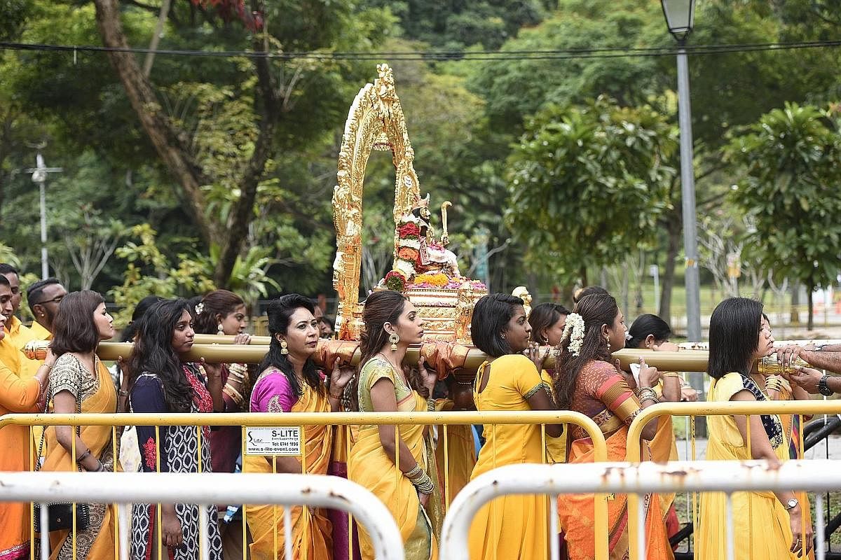 A devotee, with her tongue pierced as a form of sacrifice, carrying a pot of milk during the procession which began at Sri Srinivasa Perumal Temple in Serangoon Road yesterday. Devotees carrying kavadis - some with steel rods that pierce their skin (