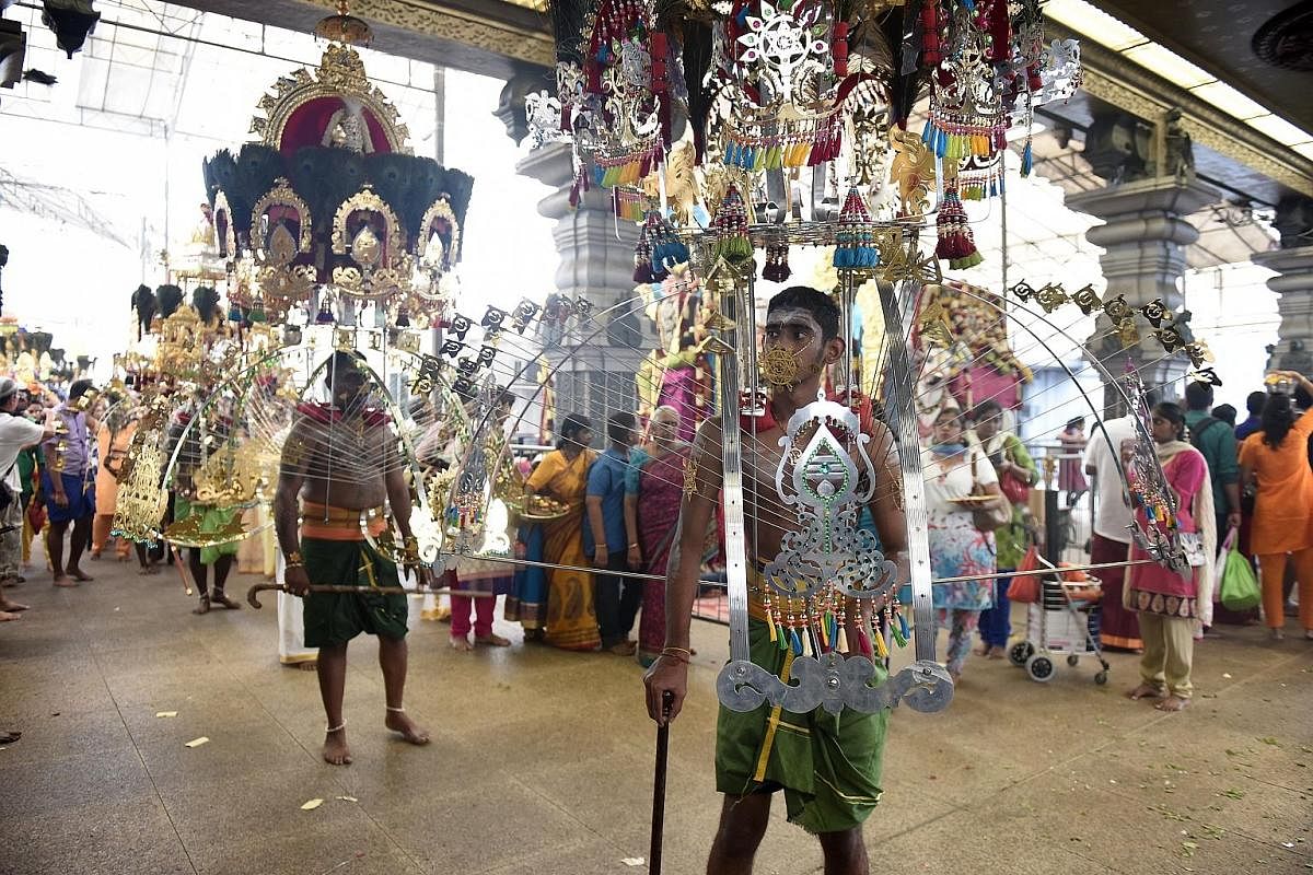 A devotee, with her tongue pierced as a form of sacrifice, carrying a pot of milk during the procession which began at Sri Srinivasa Perumal Temple in Serangoon Road yesterday. Devotees carrying kavadis - some with steel rods that pierce their skin (