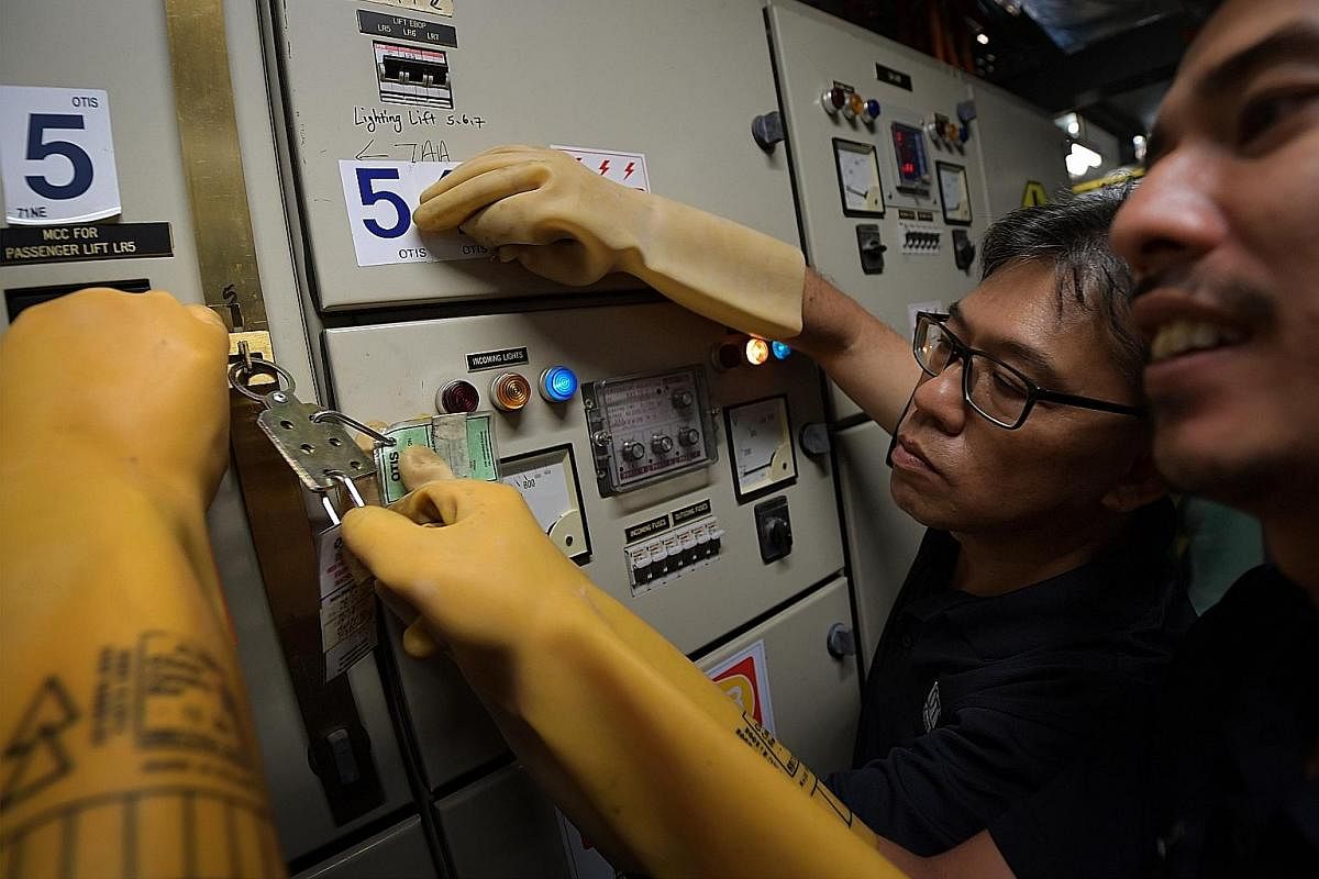Technician Mohd Iskandar Mohamad Sopi inflating a high-voltage glove to check it for tears or leaks before putting it on. This insulated glove, part of his personal protection equipment, prevents accidental electrocution on the job. Lifts are run on 
