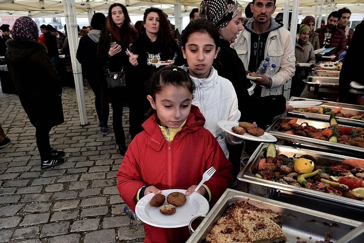 A Syrian playing a qanun, a traditional trapezoidal wooden stringed instrument. A meal cooked by refugees - some from Iraq and Syria - at a Food Uniting People #With Refugees event in the port of Thessaloniki, Greece, on March 10. Among the things Sy
