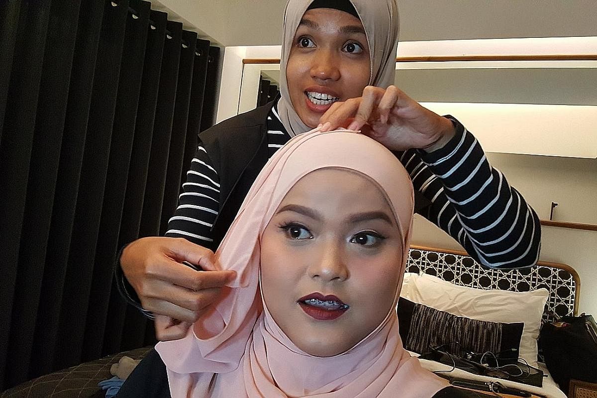Freelance make-up artist Astri Viriana at a make-up and hijab-styling session with a client. The Go-Glam platform has helped her build up her business and customer base, while allowing her to spend more time with her family. A Go-Jek rider (centre) m