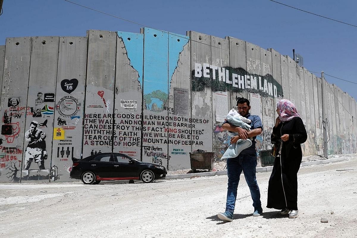 A Palestinian family walking past Israel's controversial barrier in the West Bank city of Bethlehem. The Six Day War overhauled not only the annals of military strategy - it also transformed the Middle East beyond recognition and unleashed a series o