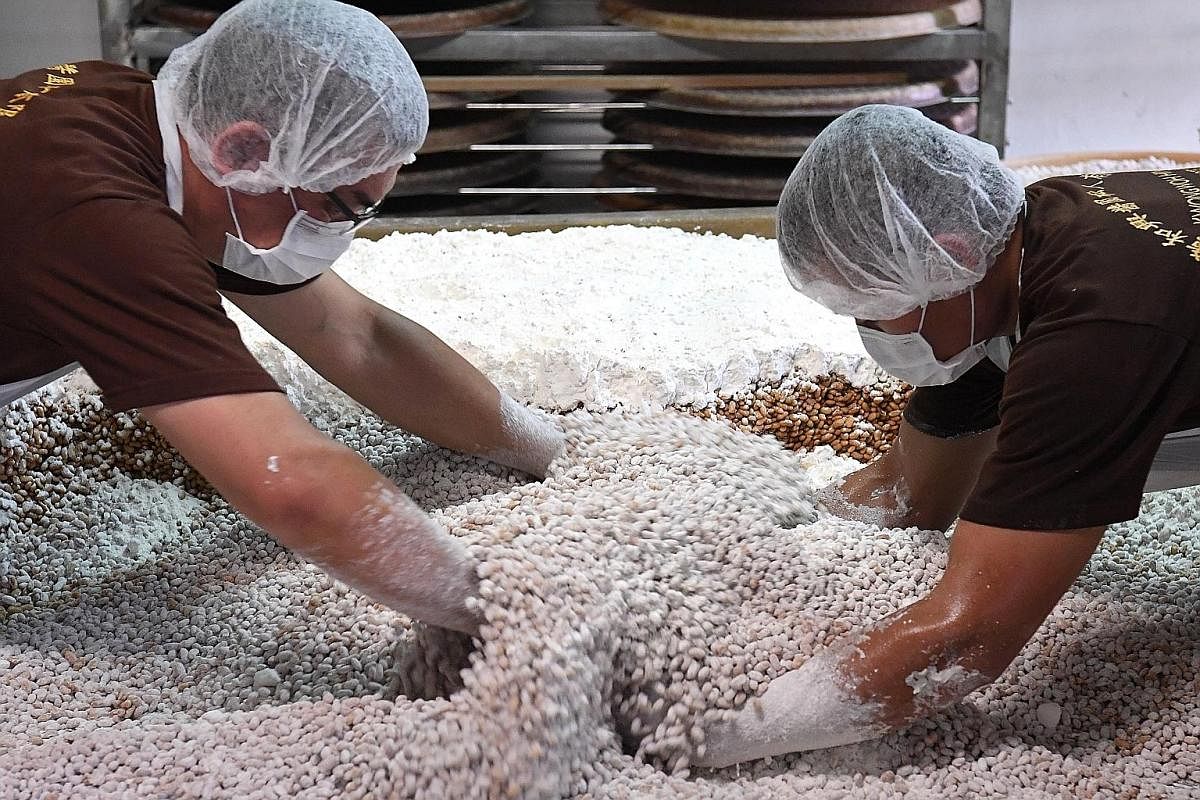 After four to seven days of fermentation indoors, the soya beans are transferred to baskets to be taken to the vats of brine in the courtyard where the fermentation process will continue under the sun. Ms Hannah Woo and factory worker Saw Lae Ka Lae 