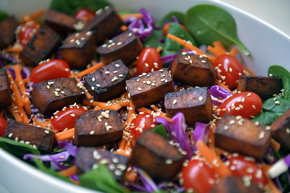 Serve the baked tofu with baby spinach, julienned carrots, purple cabbage and grape tomatoes for a healthy meal.