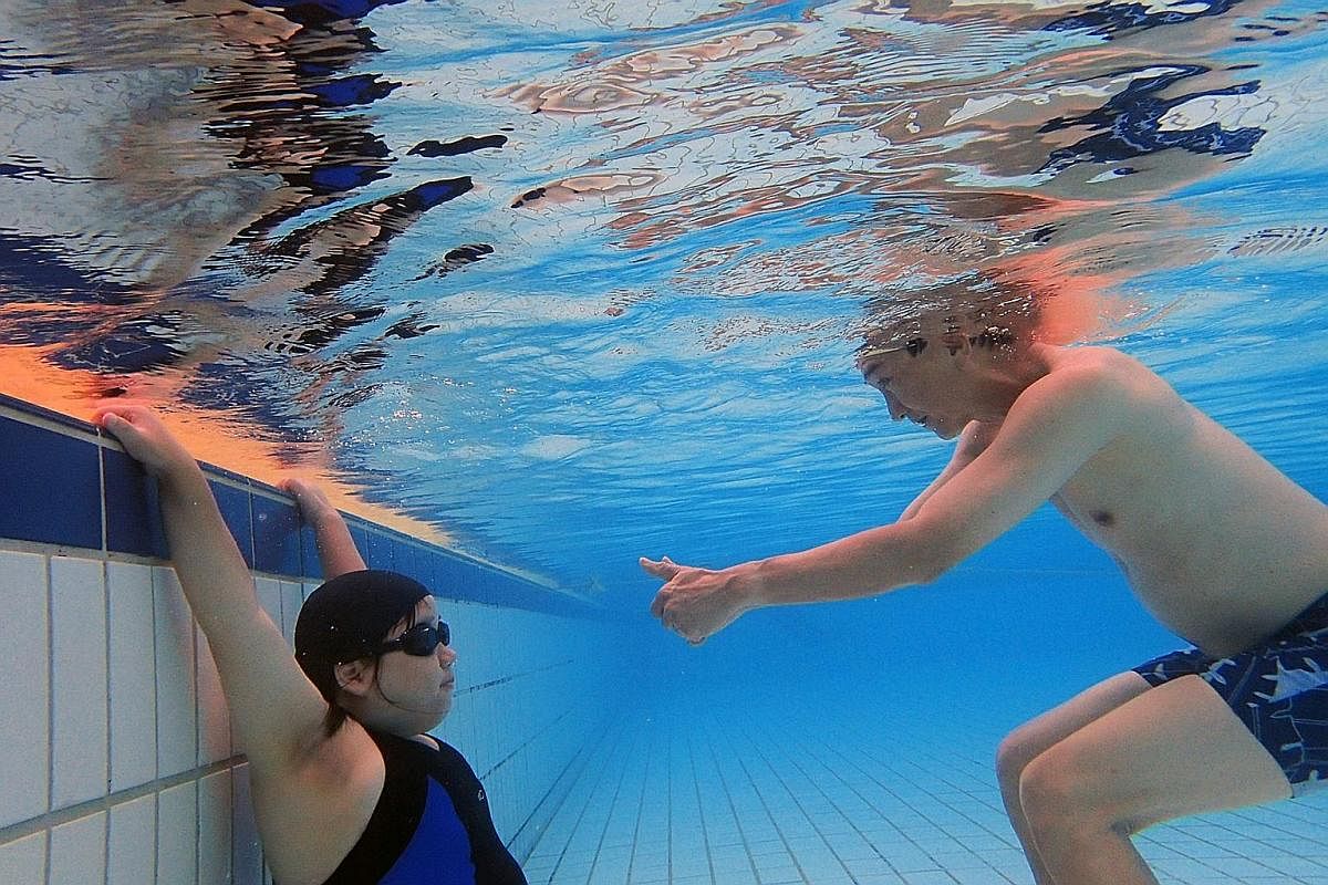 Mr Tay encourages his daughter, as she holds her breath underwater at Hougang Swimming Complex. They go swimming at least once a month as he believes that sports activities are good for Ms Tay's health and overall well-being. He adds: "We cannot make