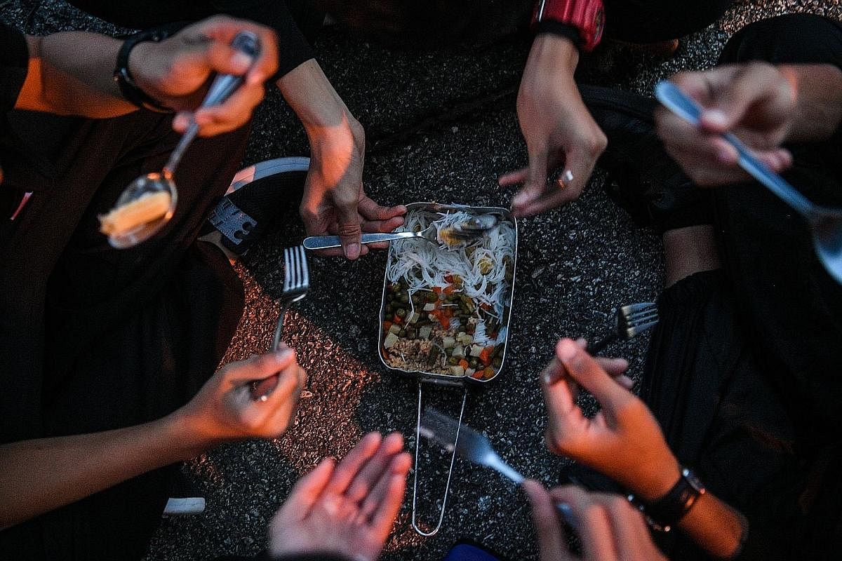 Students eat from a common mess tin during dinner time. Participants are required to cook their own meals for most of the five days and have to ration their food supplies, which include noodles, canned food, bread, isotonic-drink powder sachets and a