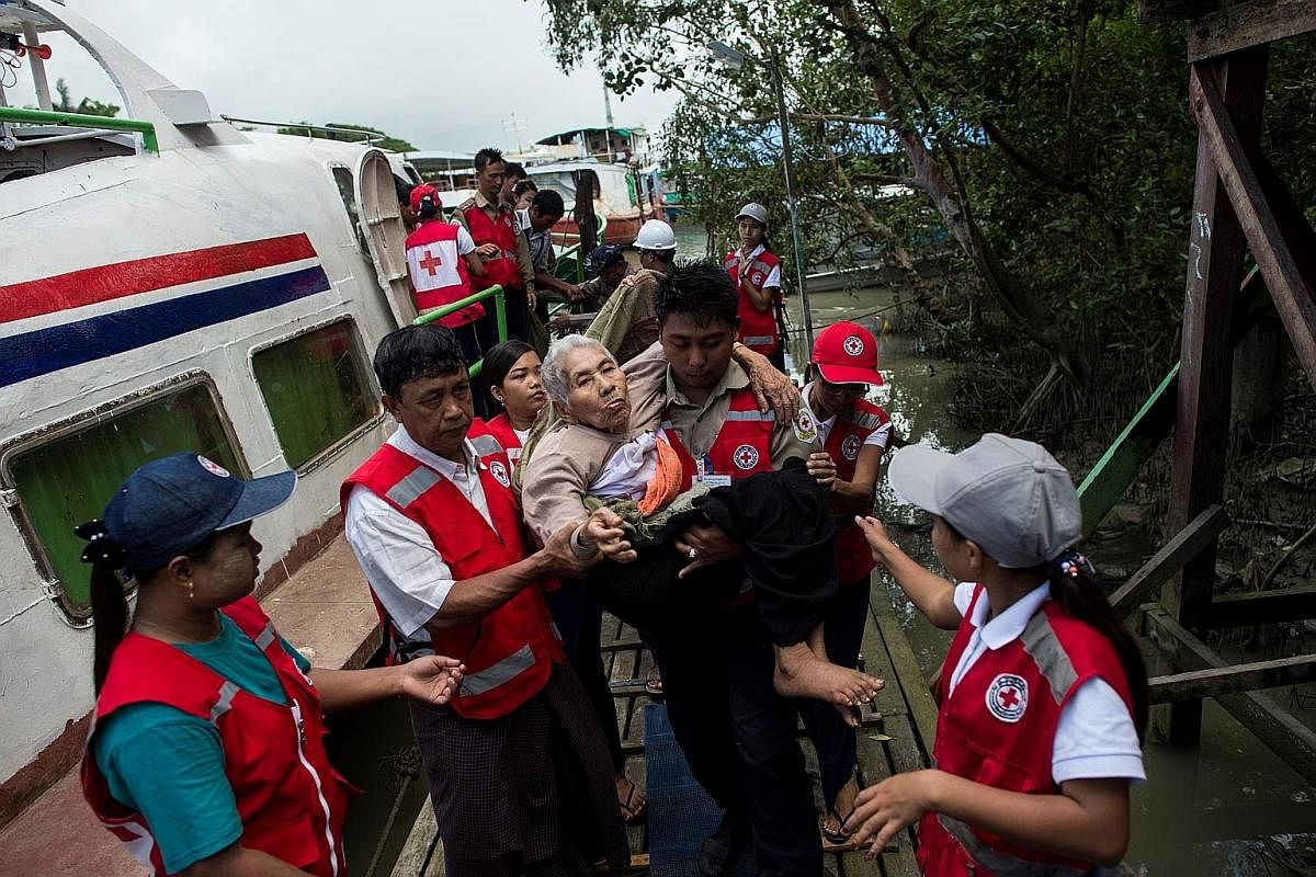 Members of Myanmar's Red Cross carrying an elderly woman from a conflict area, as she arrived at the Sittwe jetty, in Rakhine state, last Wednesday.