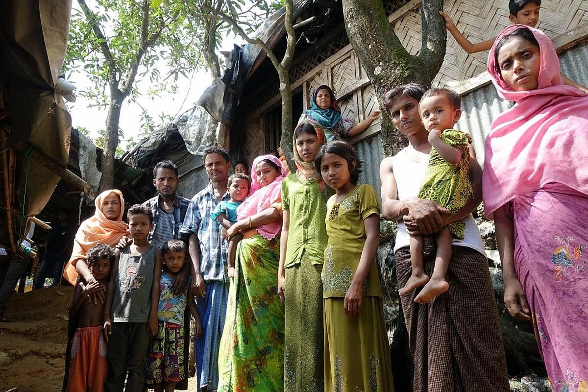Ms Roshida Begum (standing at the top), a Rohingya who fled Myanmar some 25 years ago at the age of 11, outside the shack in Bangladesh's Kutupalong refugee camp where she lives with her family, and which she also now shares with 13 other new arrival