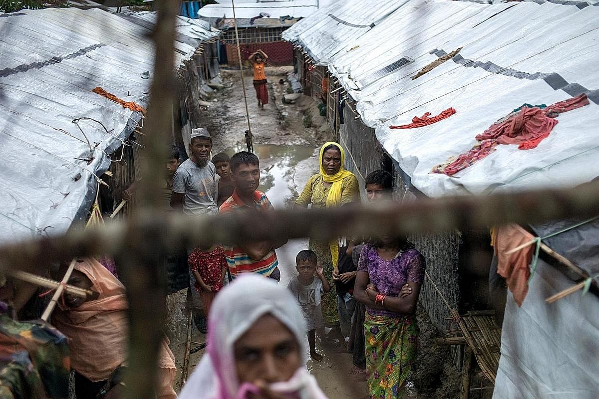 Ms Roshida Begum (standing at the top), a Rohingya who fled Myanmar some 25 years ago at the age of 11, outside the shack in Bangladesh's Kutupalong refugee camp where she lives with her family, and which she also now shares with 13 other new arrival
