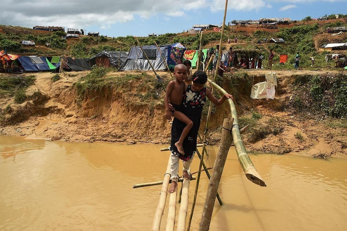 Young Rohingya refugees crossing a canal using a bamboo bridge at a newly expanded camp known as Kutupalong Extension.