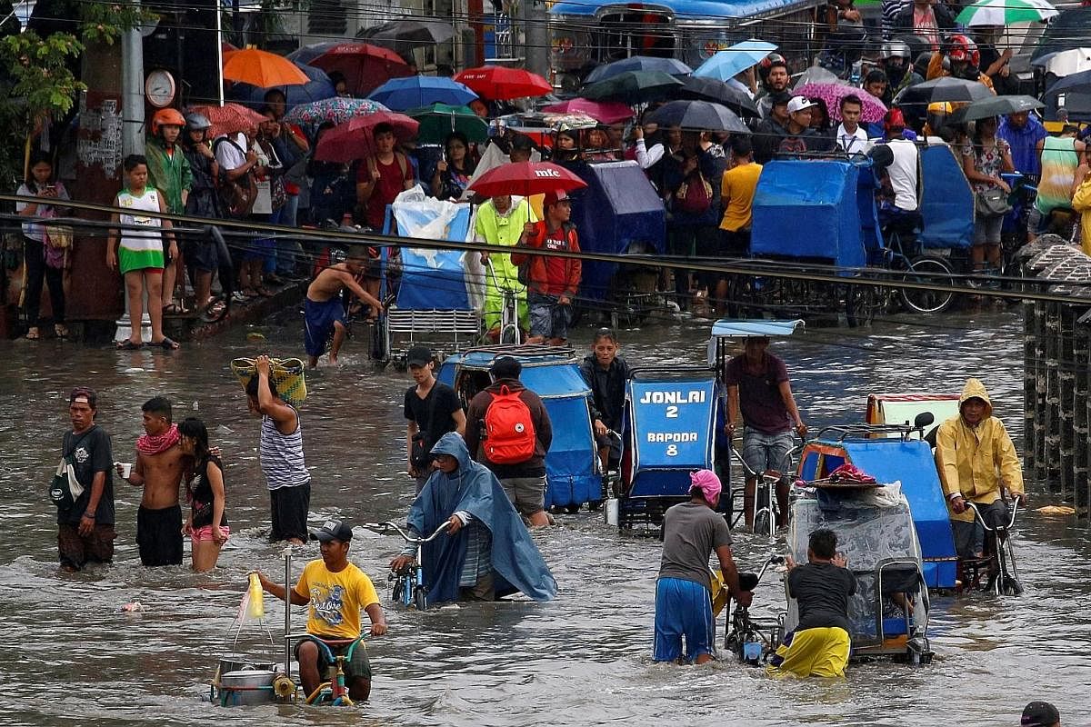 Above: Residents awaiting their turn to make their way by pedicab through floodwaters in Metro Manila last month. Left: Tacloban in the days after being hit by Super Typhoon Haiyan in 2013. Almost nothing was left standing in the trading hub of 200,0
