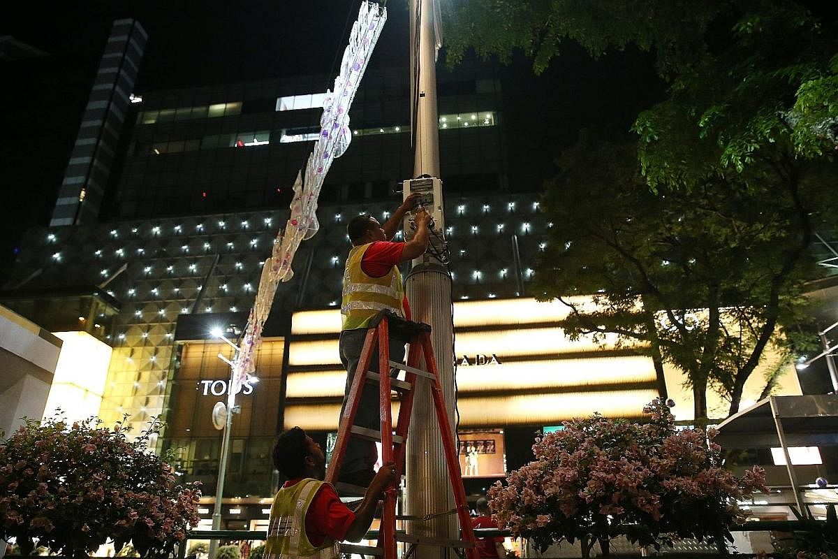 A worker arranging a globe on a tree outside the main gate of the Istana. Each globe contains various coloured fabrics intertwined with LED fairy lights. A total of 1,200 globes and 28.8km of LED lights were used to adorn the trees along Orchard Road
