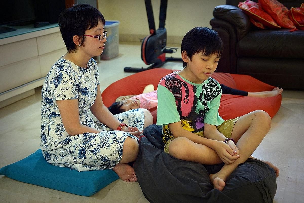 Dr Koh Li Wearn practising meditation at home with her children, Jon Yew and Jean Anne. Ms Lim Yu Lin doing a mindfulness breathing exercise with her children, Isabel and Leon.