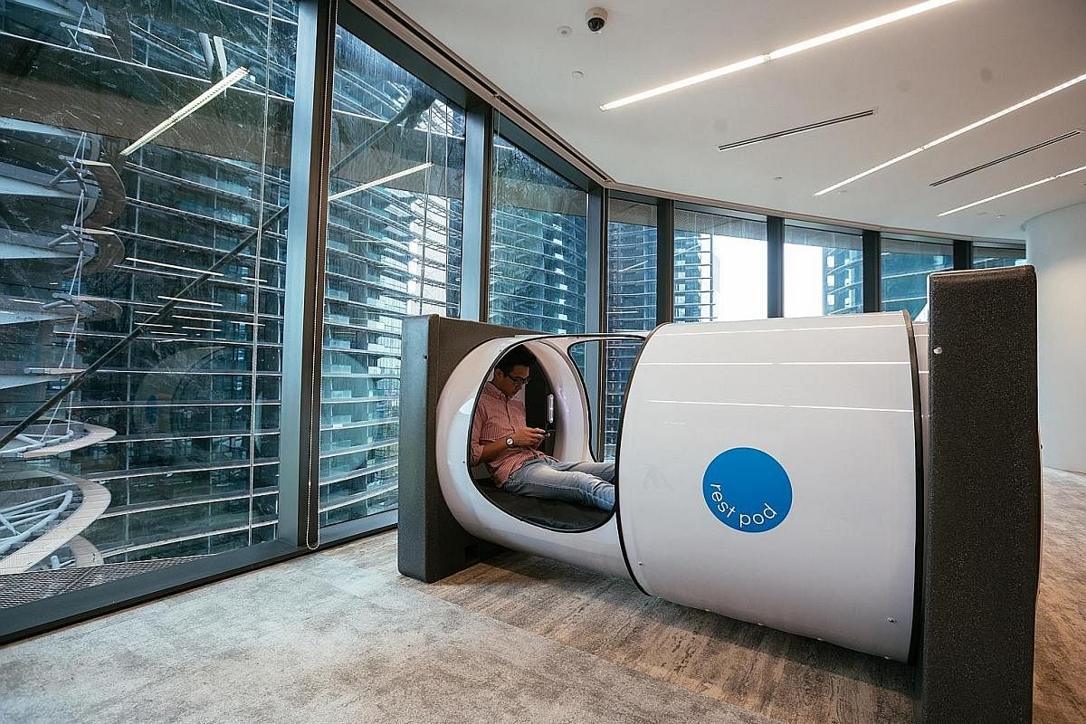 Rest pods that resemble magnetic resonance imaging machines for staff to take 40 winks. A water tunnel (above) with water cascading down the sides of the walkway at the Prudential Singapore office.