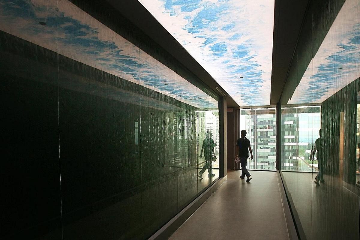 Rest pods that resemble magnetic resonance imaging machines for staff to take 40 winks. A water tunnel (above) with water cascading down the sides of the walkway at the Prudential Singapore office.