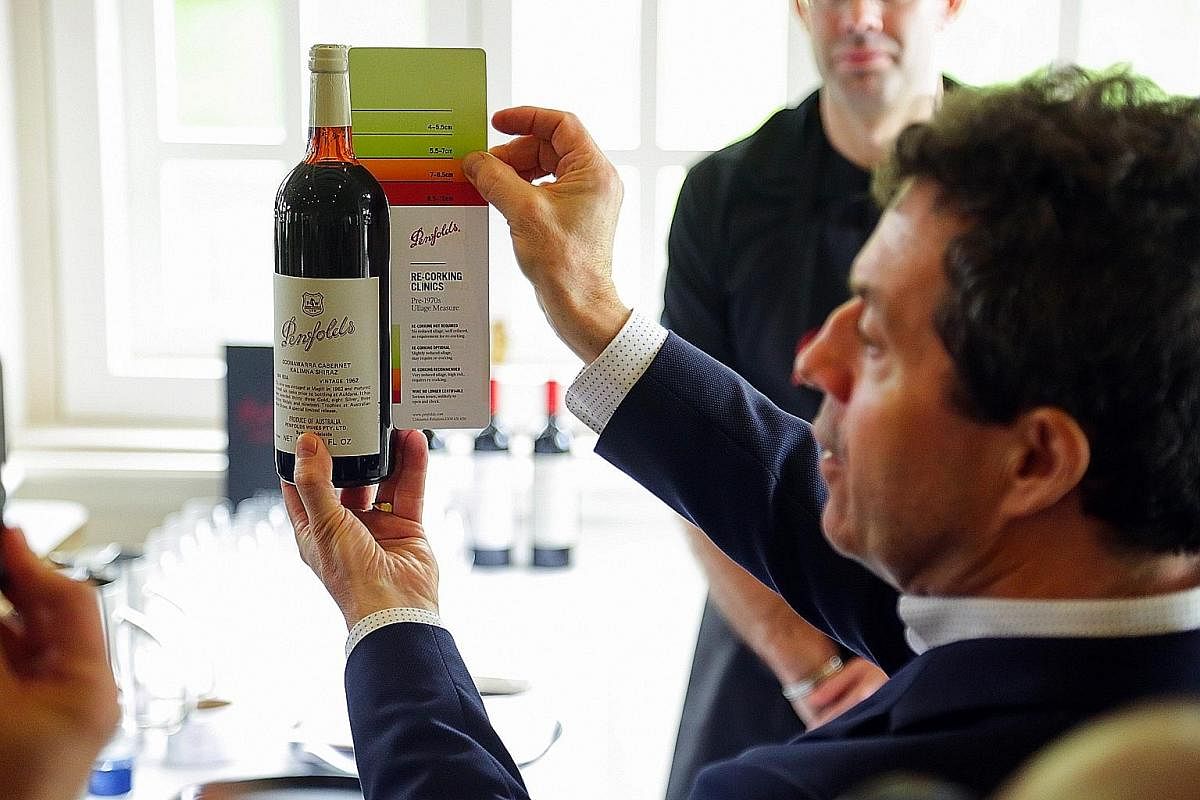 Mr Peter Gago holds up a card that helps determine the acceptable liquid level of a Penfolds bottle that is being assessed.