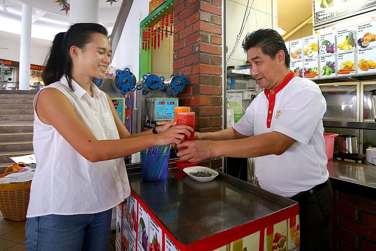 Ms Pamela Low gets her drink orders in reusable cups and without straws from Mr Henry Chua Kay Chee, who runs Fresh Fruit and Juices stall at the National University of Singapore.