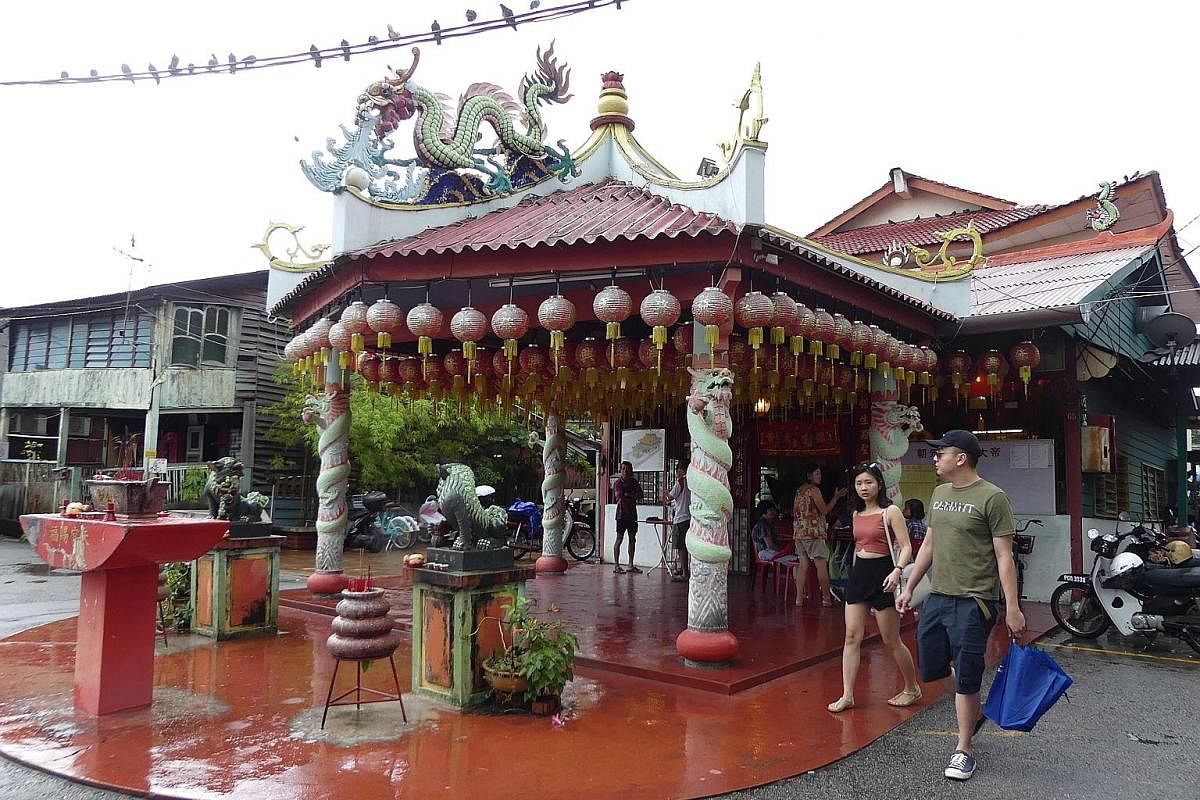 Tourists exploring Lebuh Cannon, known for its shophouses and clan temples. The culture and traditions that made George Town unique are slowly being replaced by lookalike boutique hotels and "Instagrammable" cafes. Three generations of family members