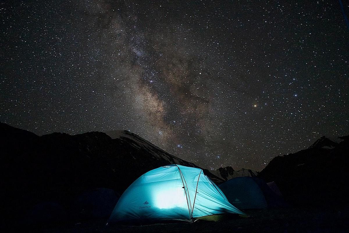 (Left) The Milky Way illuminates the night sky at the base camp of Stok Kangri. (Right) Writer Oscar Boyd and his climbing companion Anna reach the summit of Stok Kangri at 6,153m above sea level. The ascent of Stok Kangri, in the background, takes t