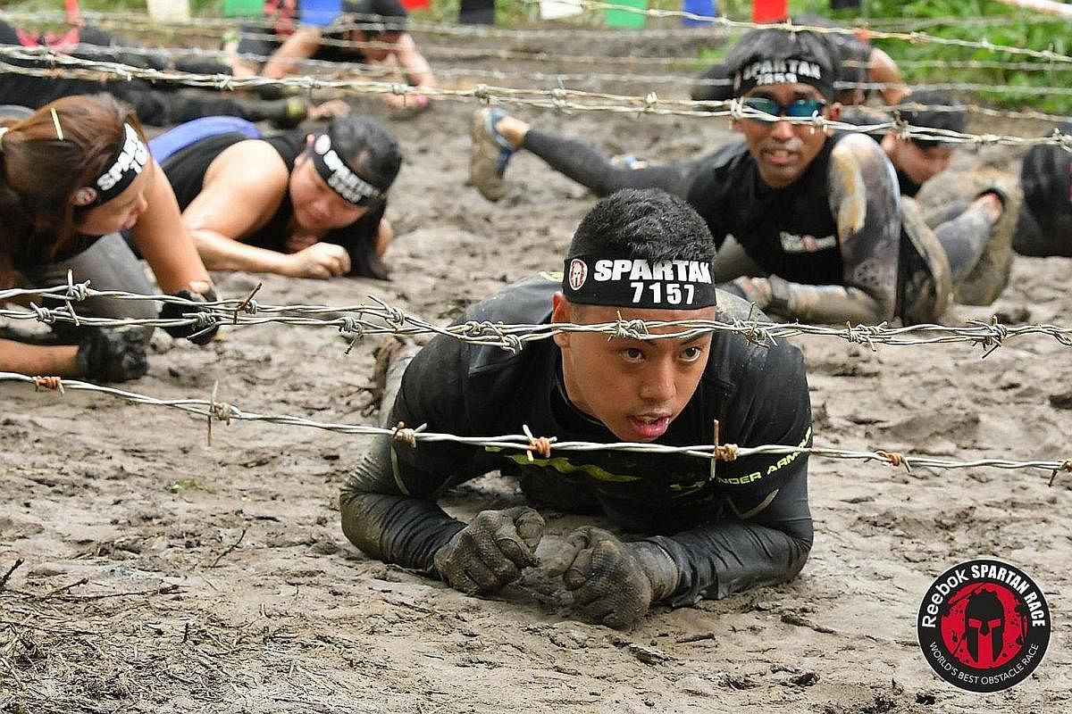 Ms Chris Hortin-Tan, who is visually handicapped, at a Spartan Singapore race in 2016. Mr Harun Rahamad, who has cerebral palsy, in a barb wire challenge at a Spartan Singapore race last year.