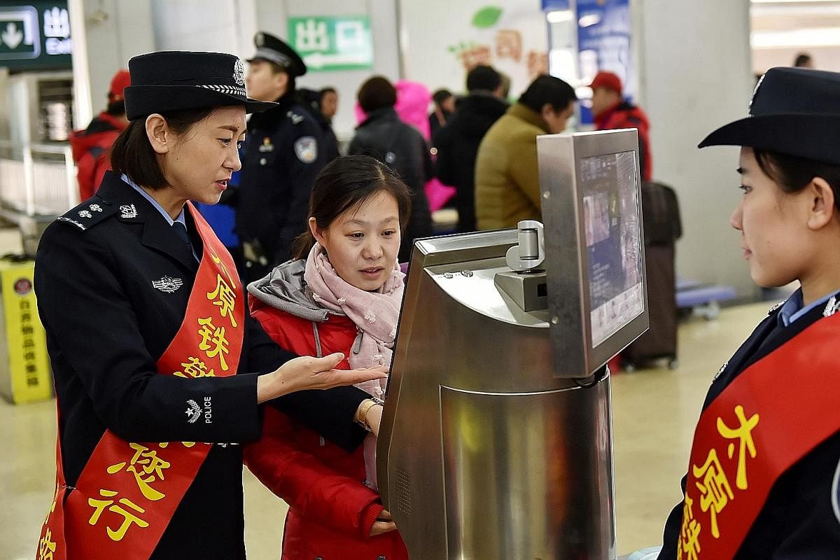 A railway policewoman helping a passenger enter the Taiyuan railway station with the help of a face recognition machine. Such machines at railway stations help to move long queues of people waiting to get their tickets checked.