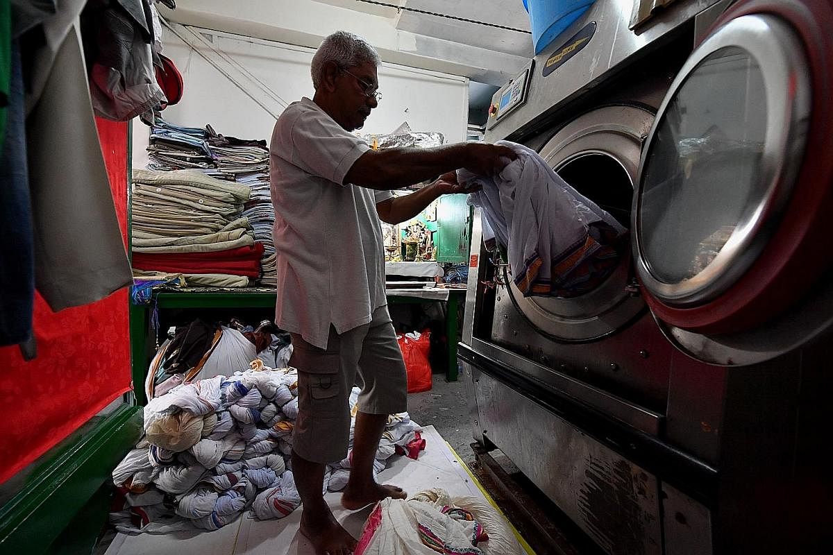 Mr Sambasivam unloading freshly washed laundry to be starched and dried later. The 73-year-old is a family friend who helps out in the shop, doing mainly administrative work. Left: After starching, the white dhotis are soaked in a pail of water with 