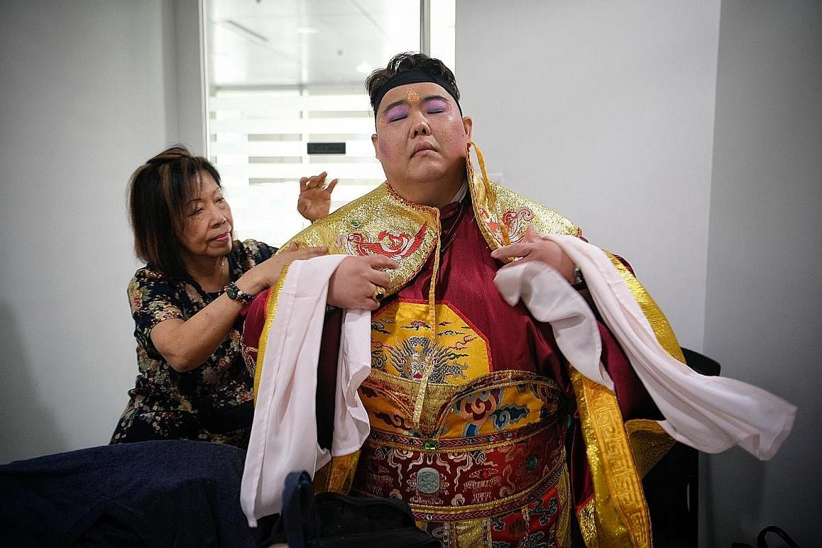 It's the end of the day, and Mr Chia finally removes his three-layered costume and makeup. He owns five outfits which he will change into halfway through events if he perspires heavily. Above: Mr Chia's mother, Madam Chua, helps him don his costume. 