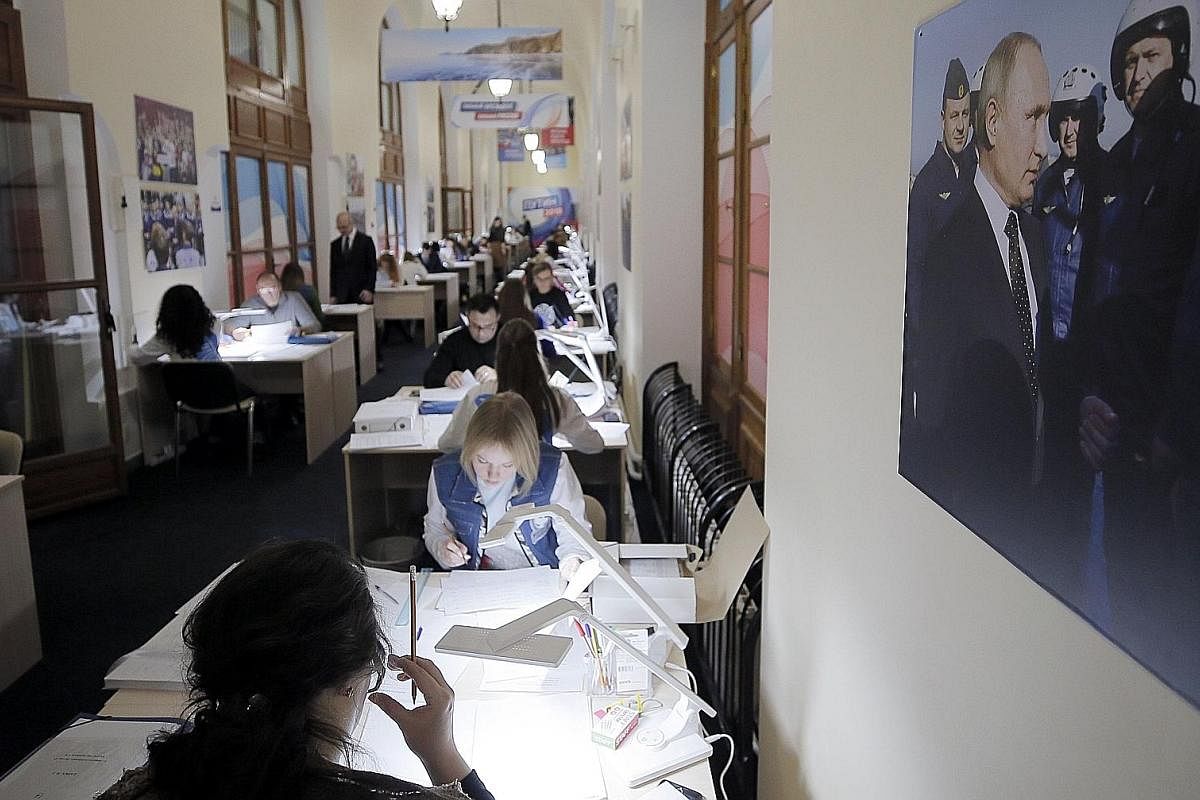 Campaign activists verifying signatures in support of Mr Putin as a candidate at his election campaign office in Moscow in January. On display at the SUPERPUTIN exhibition in Moscow's UMAM museum is this painting depicting "superhero" Russian Preside
