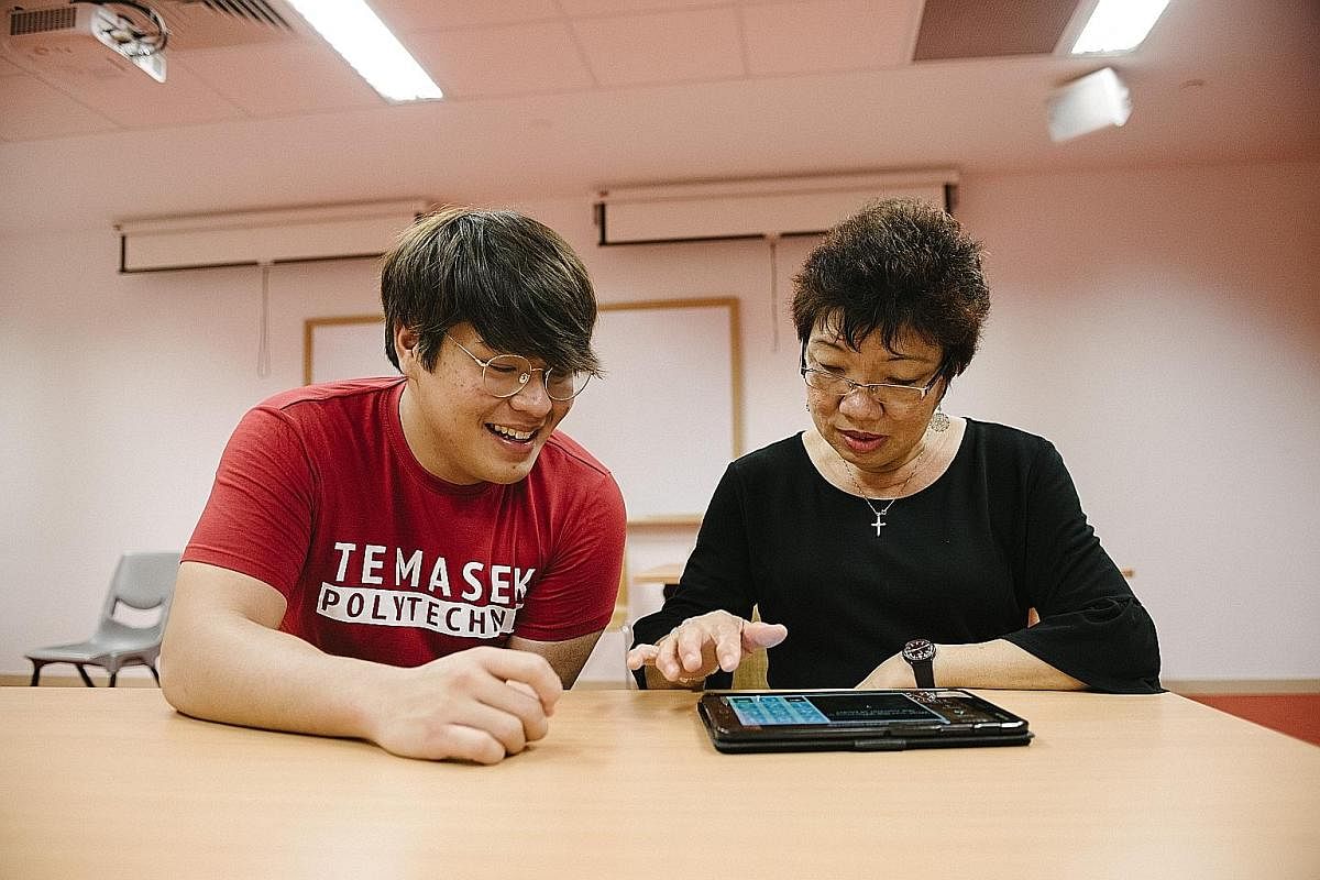 Second-year Temasek Polytechnic student Keith Zheng teaches retiree Katherine Chua how to use Mindworks, a brain-training mobile app.