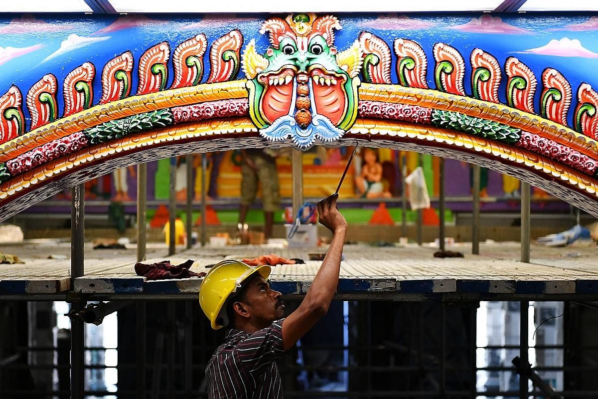 Mr Viswanathan Karunanithi (left), 47, and Mr Karuppaiyan Chidambara-nathan (right), 48, two of the 20 skilled temple artisans from India, painting motifs representing Indian astrology signs on the ceiling above the Garudar sanctum. The men are worki